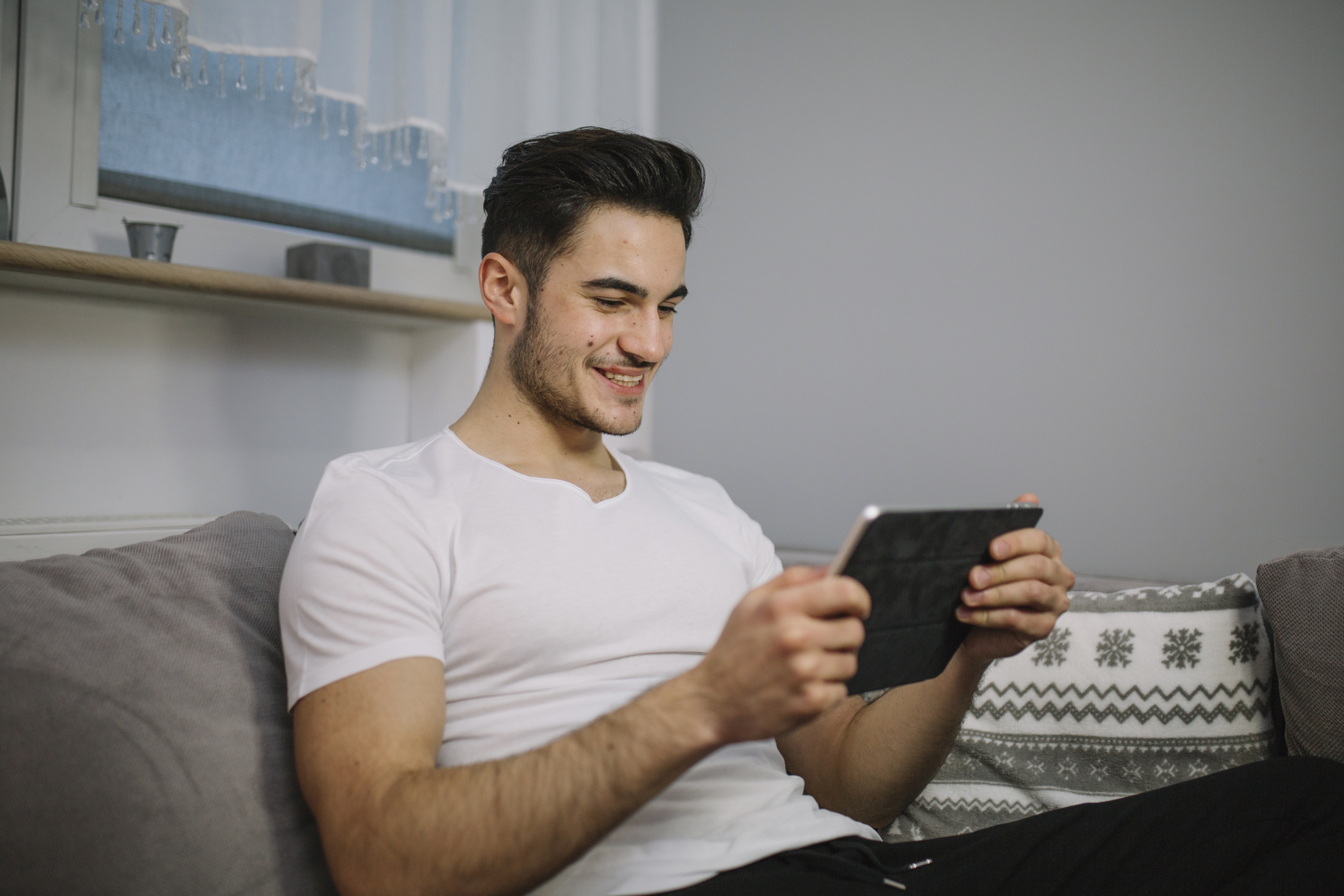 smiling-man-using-tablet-couch.jpg